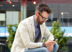 man concentrating on reading his mobile phone, engaging in online therapy